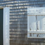 photo of the side of a cottage with white wearing paint