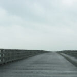 dark grey image of a wooden bridge and cloudy sky, rain